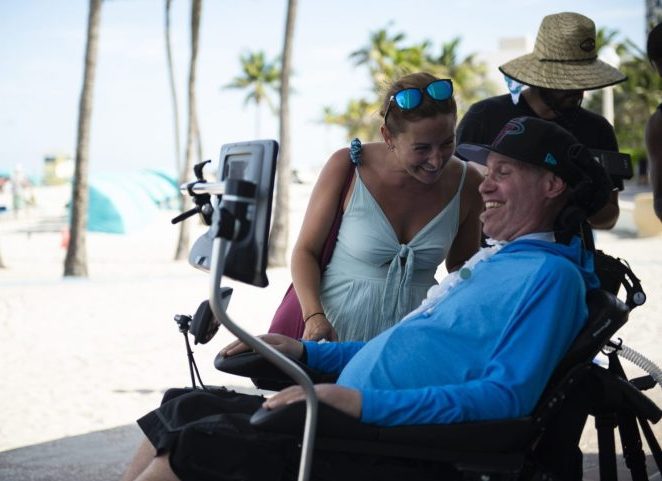 Personne en fauteuil roulant électrique atteinte de la SLA communique avec les yeux