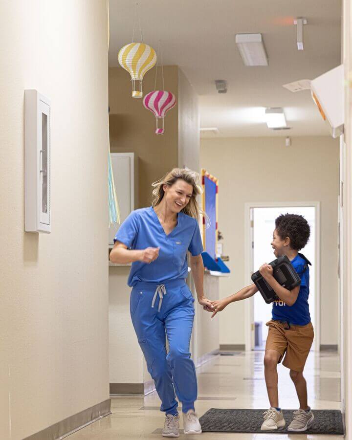 Ergothérapeute accompagnant un enfant autiste avec une tablette de communication alternative et améliorée